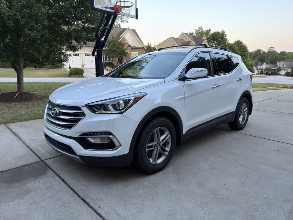 Freshly washed white Hyundai Santa Fe parked in a driveway at sunset
